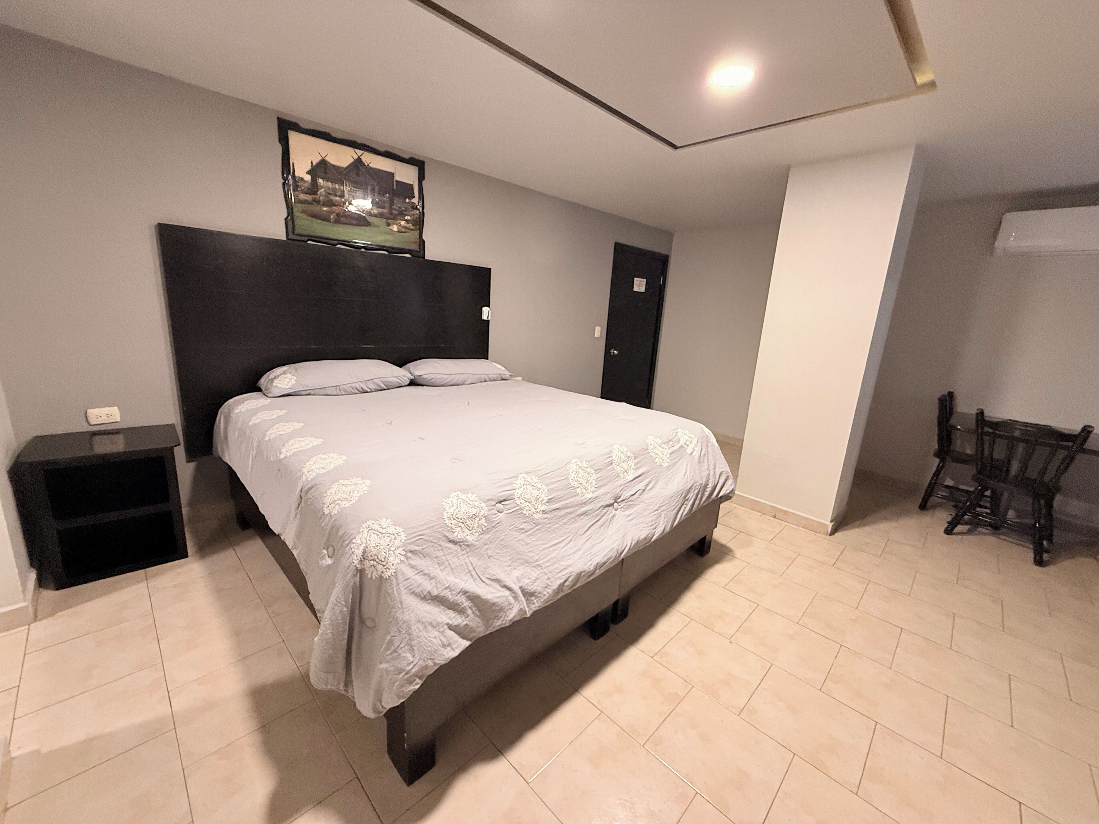 A bedroom with a bed, a nightstand, a chair, and a door.