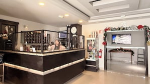 A modern reception area with a black counter, a clock, and a TV screen. - Hotel Nieto Express (Matamoros)