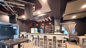 A bar area with a bar counter, seating, and a refrigerator. - Hotel Nieto Express (Matamoros)