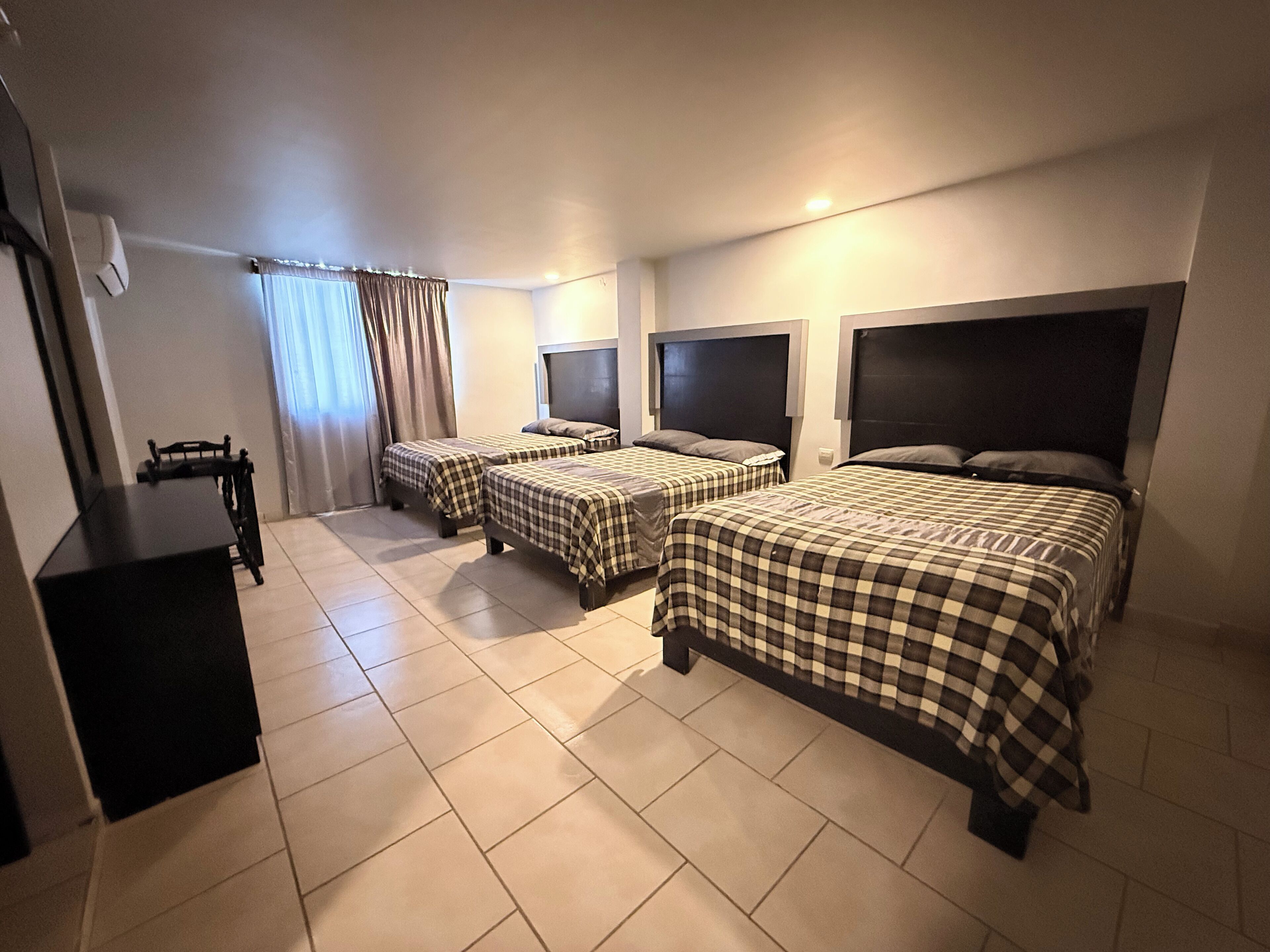 A hotel room with three beds, a desk, and a chair.