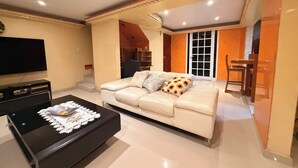 Un salon comprenant un canapé, une table basse, un téléviseur et un coin repas avec des chaises et une table.