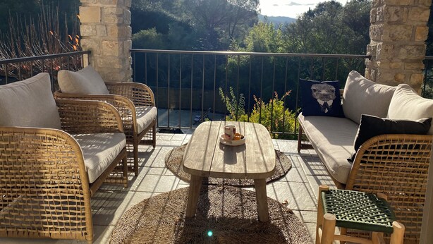 A sunlit outdoor seating area with wicker furniture and a wooden table, overlooking a lush garden and distant hills. - Mas Tihou charming Provencal estate✨& Nordic bath 🫧 (Le Beausset)