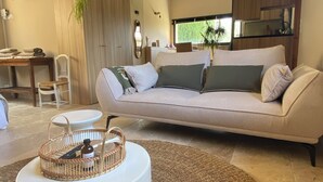 A modern living room with a beige sofa, a round white coffee table, and a woven rug. - Mas Tihou charming Provencal estate✨& Nordic bath 🫧 (Le Beausset)