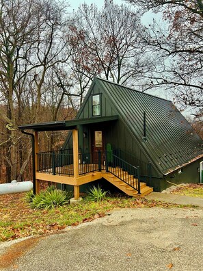 Ein kleines, dunkelgrünes Gebäude mit einem geneigten Dach und einer Holterrasse.