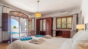 Ein Schlafzimmer mit Bett, Schreibtisch, Stuhl, Pendelleuchte und einem Fenster mit Blick.