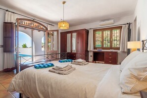 A bedroom with a bed, a desk, a chair, a hanging light fixture, and a window with a view. - Luxury villa for 7 guests, pool and sea view with 3 acres of almond grove (Casabermeja)