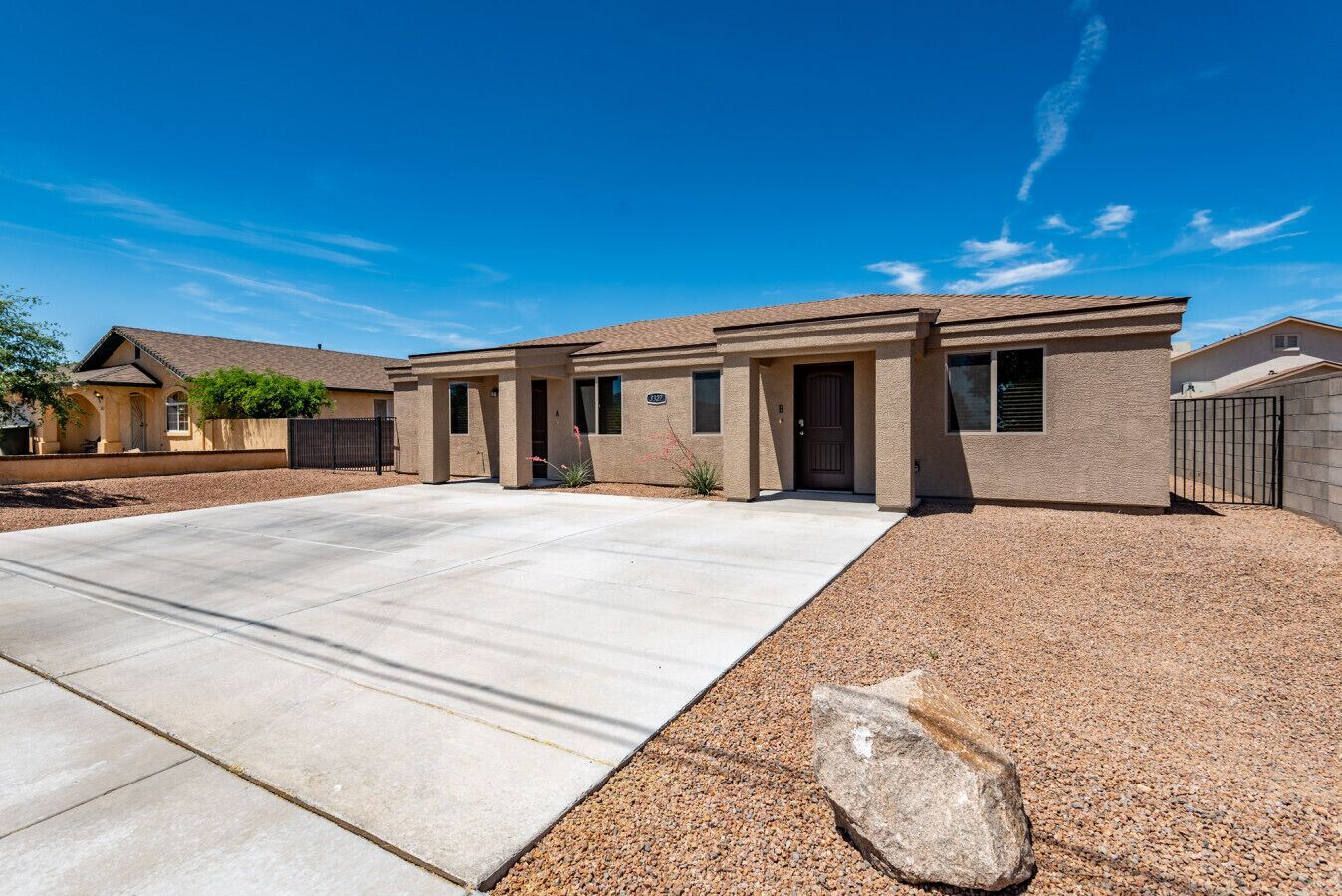 A single-story house with a concrete driveway and a gravel area.