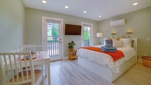 Un dormitorio con cama, mesitas de noche, televisor y ventana.