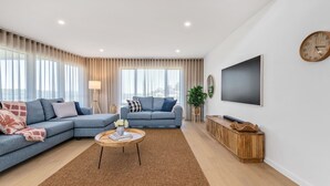 A modern living room with two sofas, a coffee table, a TV, and a clock on the wall. - Marys Tide & View Vista at Long Beach (Long Beach)