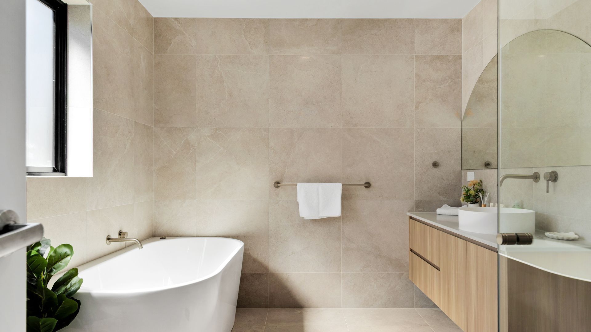 Une salle de bain moderne avec une baignoire sur pieds, un meuble-lavabo avec un miroir et un porte-serviettes.