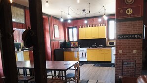 A kitchen with yellow cabinets, a white stove, and a black countertop. There is a dining table with chairs and a rug on the floor. - GITE DE GROUPES 210m2, sleeps 15, pets welcome! (Cransac)