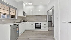 A modern kitchen with white cabinets, a built-in oven, a microwave, and a dishwasher. - Cessnock Country Gateway to Vineyards View (Cessnock)