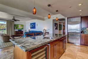 A modern kitchen with a marble countertop, stainless steel appliances, pendant lighting, and a large island. - Honua Kai | Ocean View 5 BR, Sleeps 14 | Car Incl. w/ 6+ Nights | HKH ML-2588 by KBM (Lahaina)