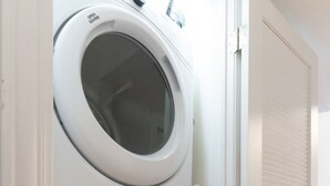 A stacked washer and dryer unit in a hallway with a door on the right. - Flexhome Wicker Park • Stylish 2BR • Sleeps 6 (Chicago)
