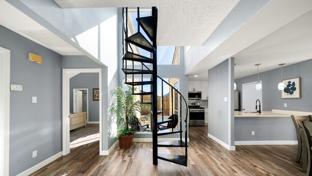 A spacious interior with a central spiral staircase, wooden flooring, and a kitchen area. - Houston Energy Corridor Home (Houston)