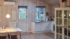 A compact kitchen with white cabinets, a dining table with chairs, and a cabinet with glass doors. - Lovely home in Sjølund with WiFi (Sjølund)