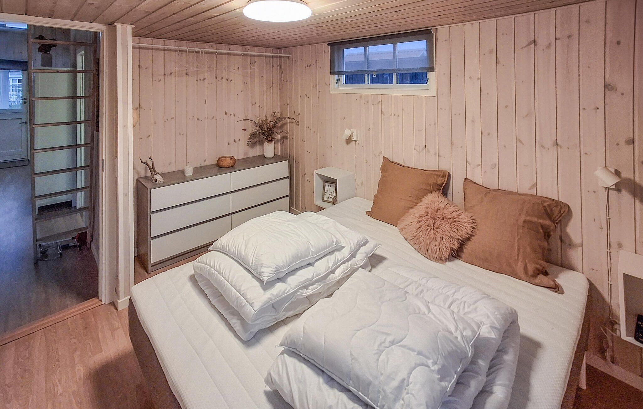 A bedroom with a bed, a dresser, a window, and a nightstand.