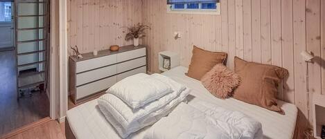 A bedroom with a bed, a dresser, a window, and a nightstand.
