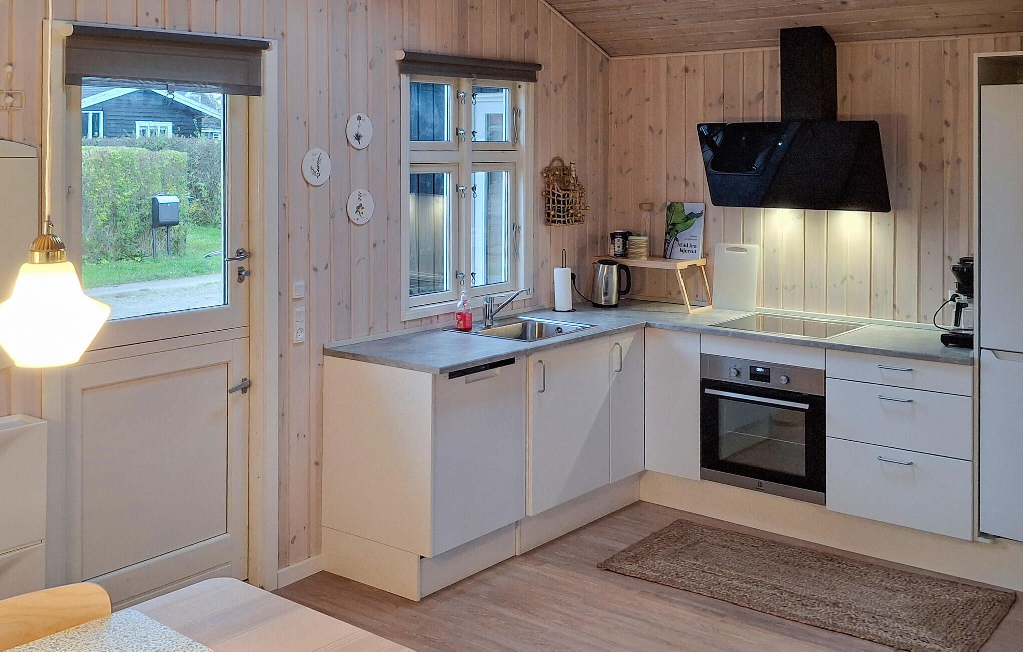 A modern kitchen with wooden cabinets, a sink, a stove, and a coffee machine.