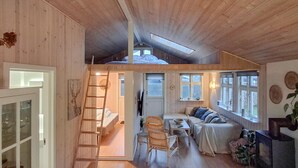 A loft-style bedroom with a skylight, a wooden staircase, a sofa, and a dining area. - Lovely home in Sjølund with WiFi (Sjølund)