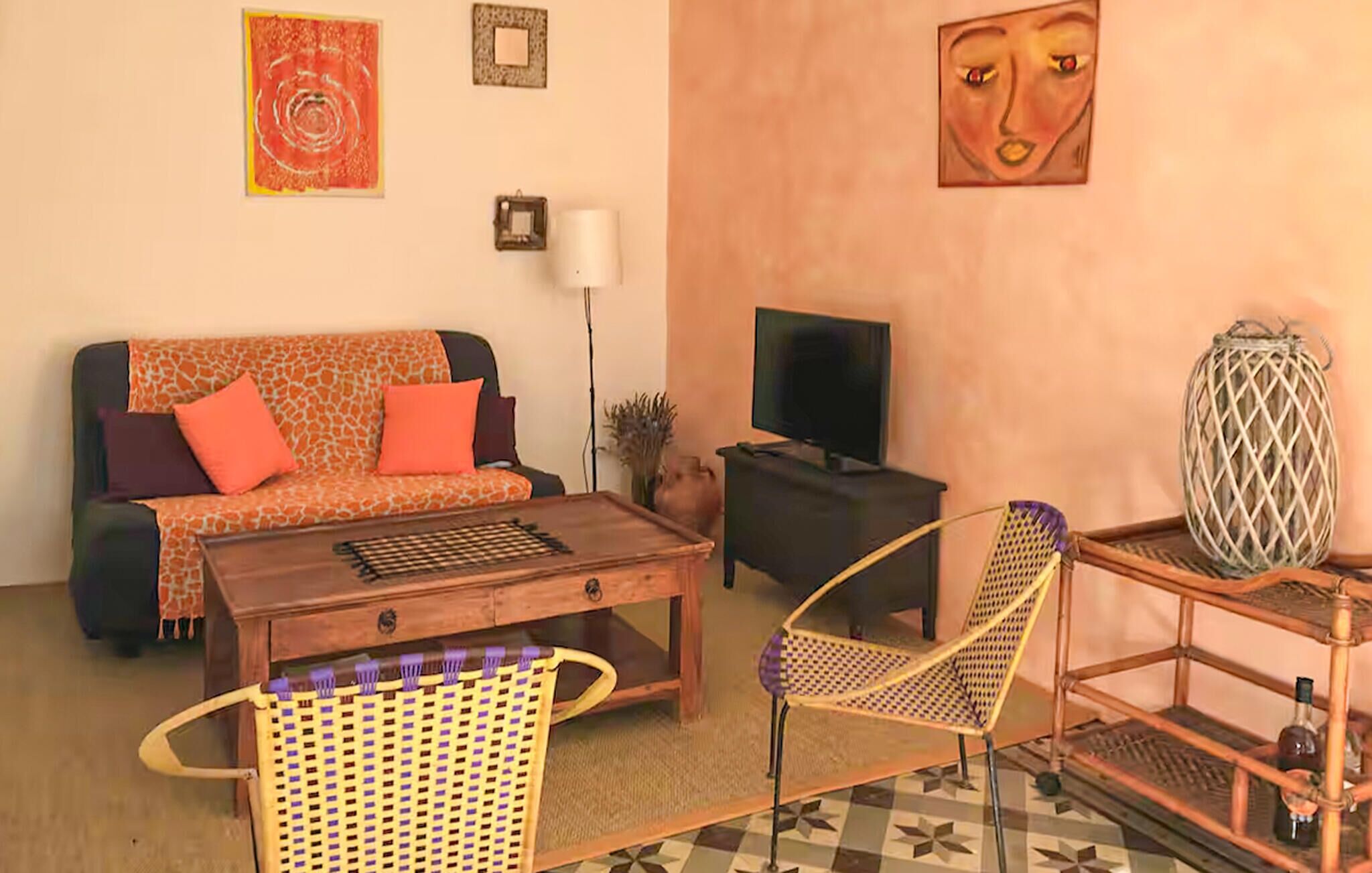A living room with a sofa, coffee table, two chairs, a TV, and decorative items on the wall.