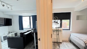 Un apartamento moderno con kitchenette, un sofá, una cama y un ventanal grande.
