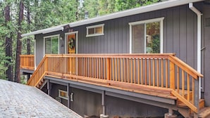 Eine zweistöckige Holzhütte mit einer Holzterrasse und einer kleinen Veranda.