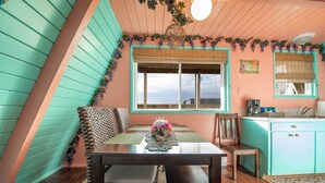Una habitación acogedora con una mesa de comedor, sillas, una ventana, un lavabo y una zona de cocina.