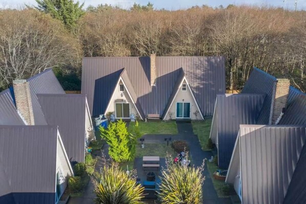 Un ensemble de chalets en forme de « A », regroupés autour d’une cour centrale, le tout entouré d’arbres.