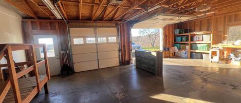 Eine Garage mit Betonboden, Holzbalken, einer Werkbank und Regalen.