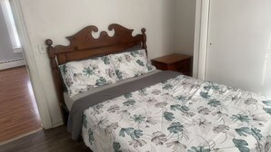A bedroom with a wooden headboard, floral bedding, a bedside table, and a wooden floor. - 2-bedroom house in Springfield (Springfield)