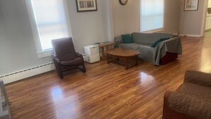 A living room with hardwood flooring, a sofa, a chair, a small table, and a heater. - 2-bedroom house in Springfield (Springfield)