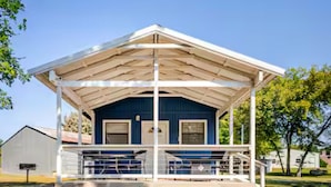 A blue building with a covered porch and a white roof. - Bixby Cove Cabin #3 (Porum)