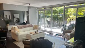 Una sala de estar moderna con un amplio ventanal corredizo que da a un patio.