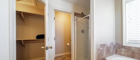 Un baño con cabina de ducha de vidrio, bañera y armario vestidor con puerta.