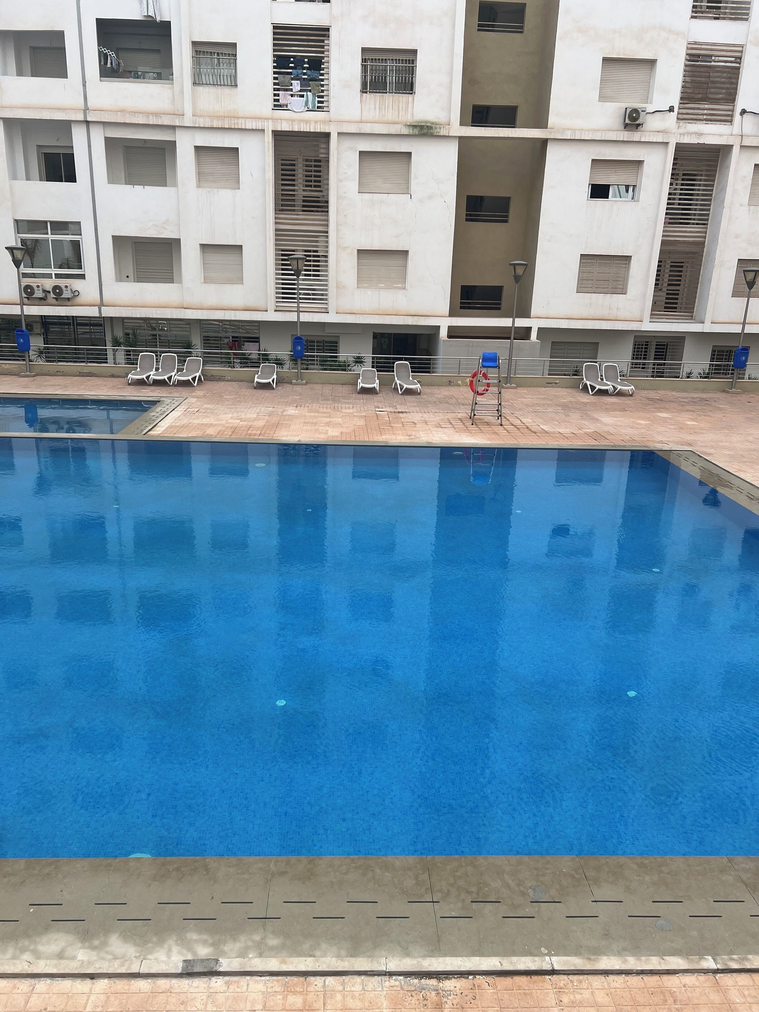 A swimming pool with lounge chairs and a building in the background.