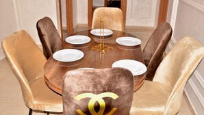 A round dining table with six velvet chairs, each with a visible logo. - Apartment agadirparking wifi swimming pool (Agadir)