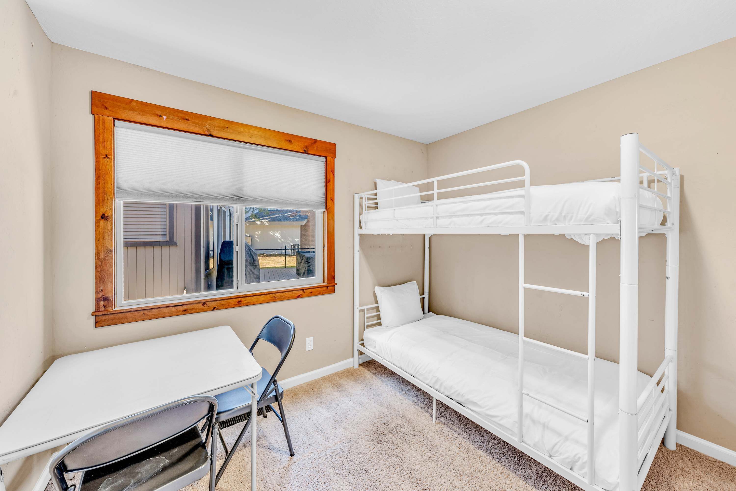Habitación con literas, una ventana, un escritorio y una silla.
