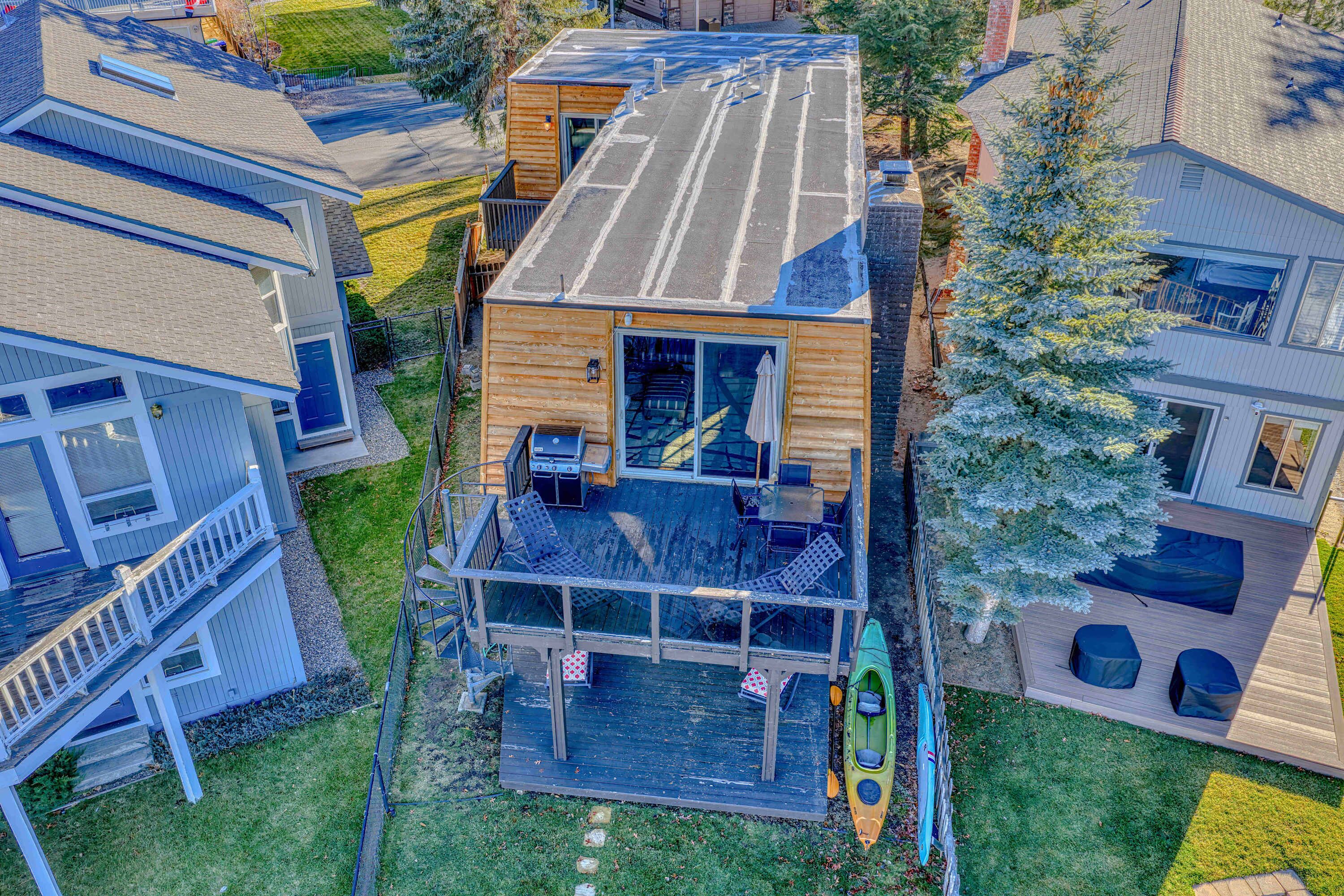 A multi-level wooden house with a deck, outdoor seating, and a kayak.