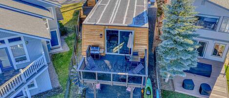 A multi-level wooden house with a deck, outdoor seating, and a kayak.