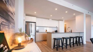 Una cucina moderna con mobili bianchi, un'isola centrale con sgabelli da bar e un pavimento in legno.