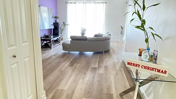 Een ruime woonkamer met een grijze modulaire bank, een plafondventilator en een bord met de tekst 'Merry Christmas'.