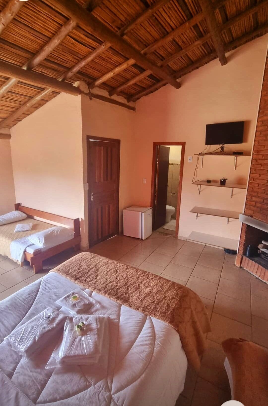Een kamer met een bed, een kleine koelkast, een televisie en een open haard.