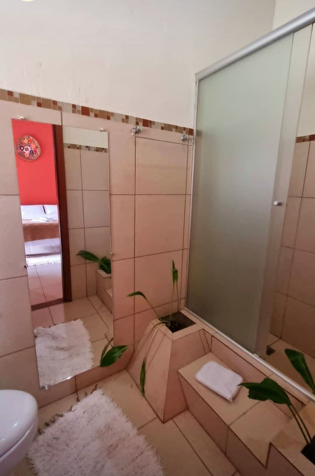 A bathroom with a shower, a toilet, a sink, and a mirror.