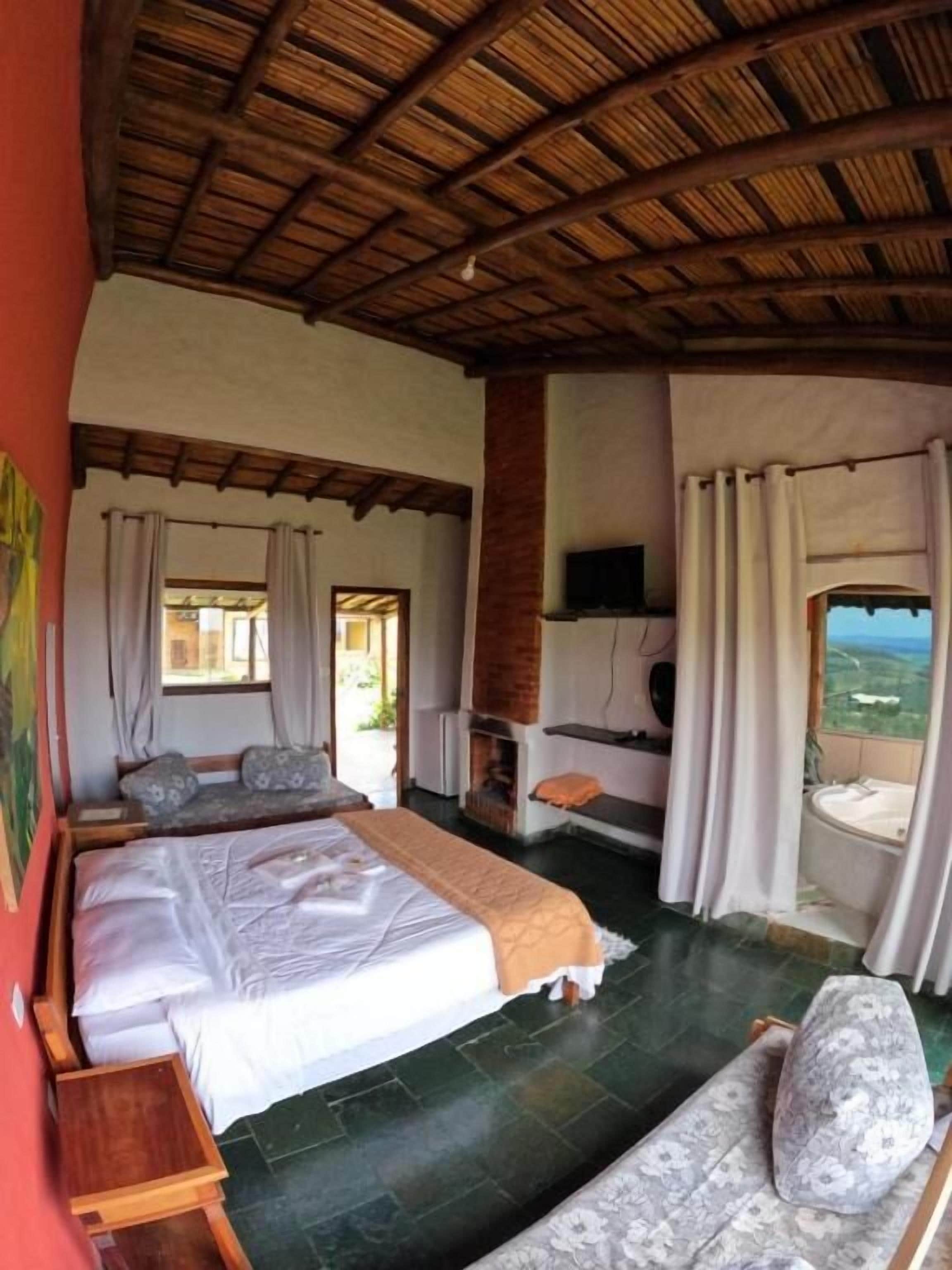 A bedroom with a large bed, a sofa, a TV, and a view of the landscape.