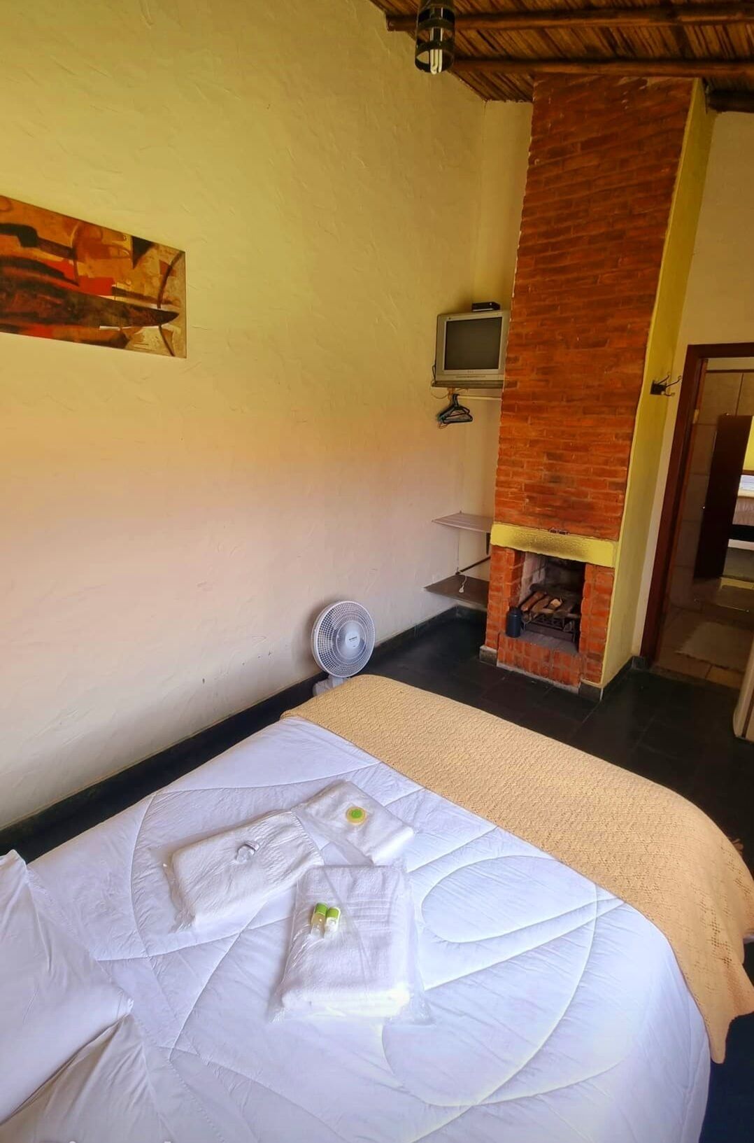 Habitación de hotel con cama, televisión, ventilador y chimenea.