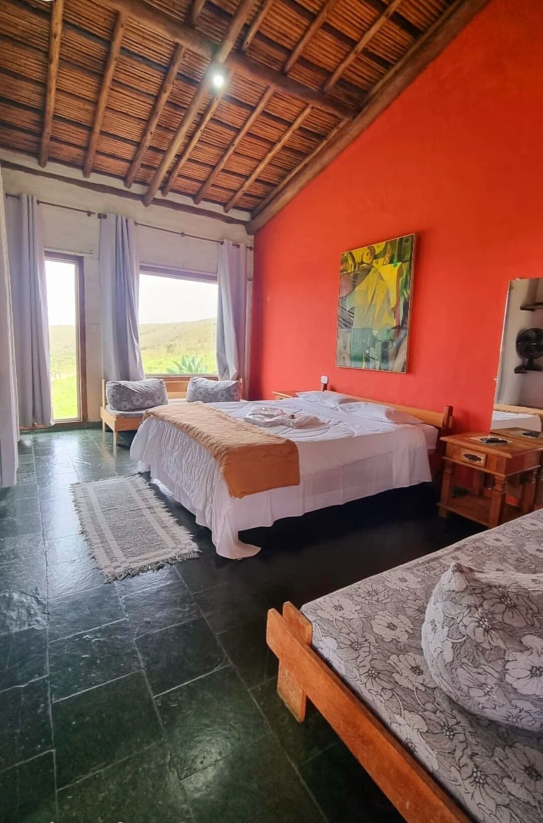 Una habitación con una cama, un banco de madera, una mesa y un cuadro en la pared.