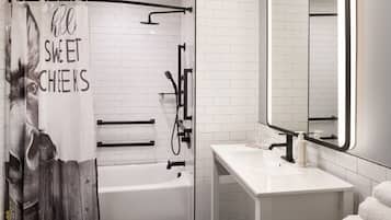 A modern bathroom with a white bathtub, a shower with a black curtain, a white sink, and a mirror.