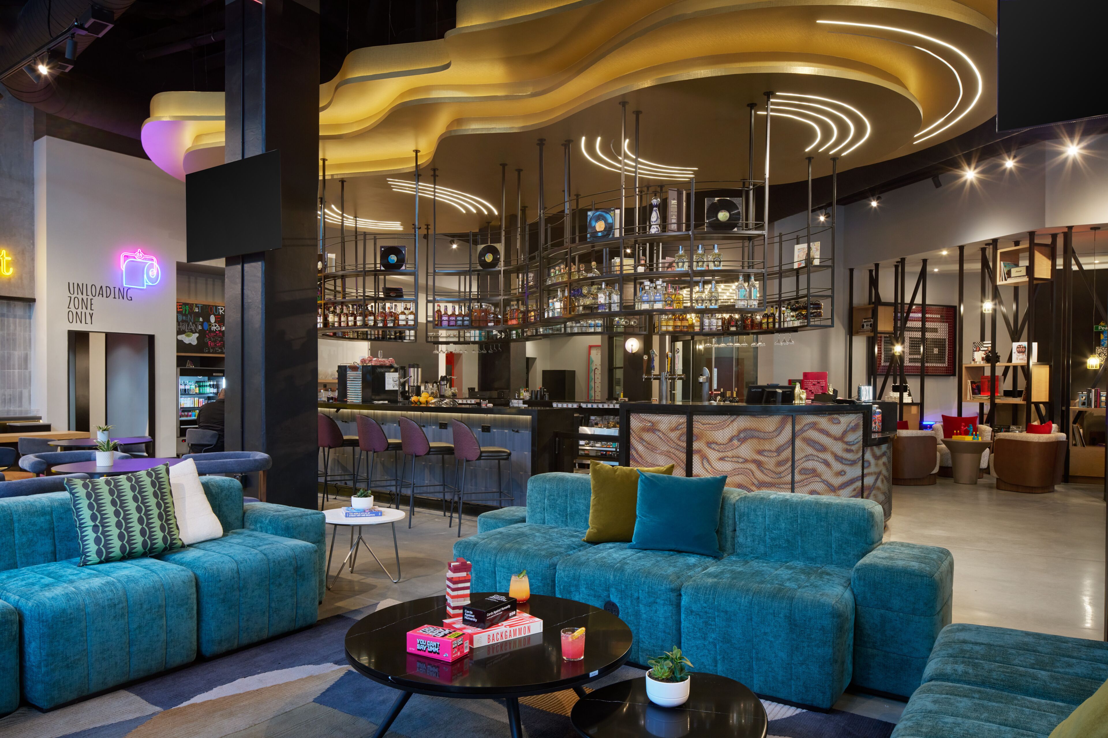 Un área de estar moderna con sofás, un bar y una zona de asientos con una mesa redonda.