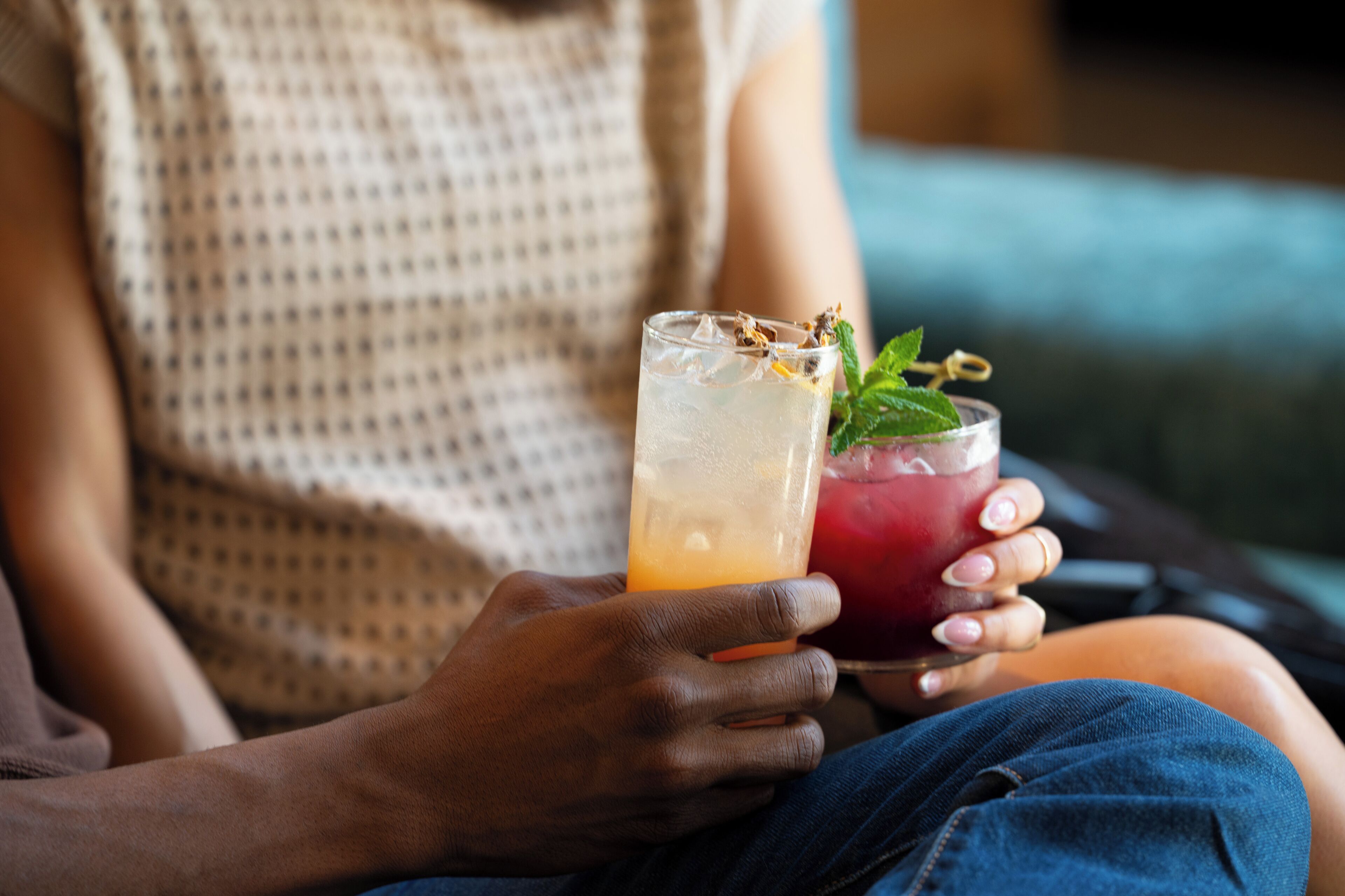 A person holding two drinks, one in each hand.
